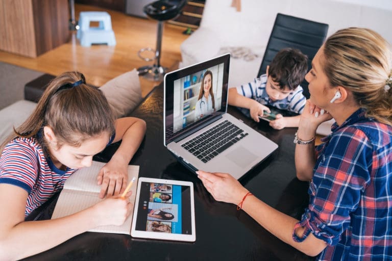 Mother trying to talk with doctor on laptop while watching two kids staying home.