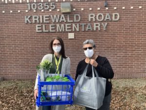 Educadores con máscaras, flores y obsequios de Firstmark en la escuela primaria Kriewald.