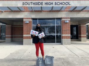 Educator holding masks in front of Southside High School.
