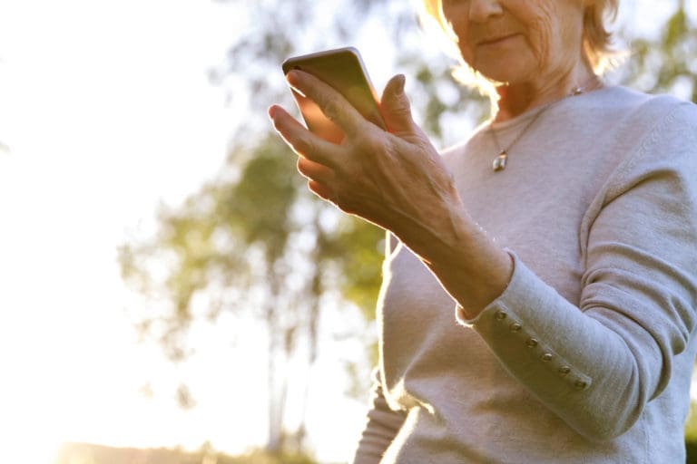 Elderly woman is holding a phone reading text