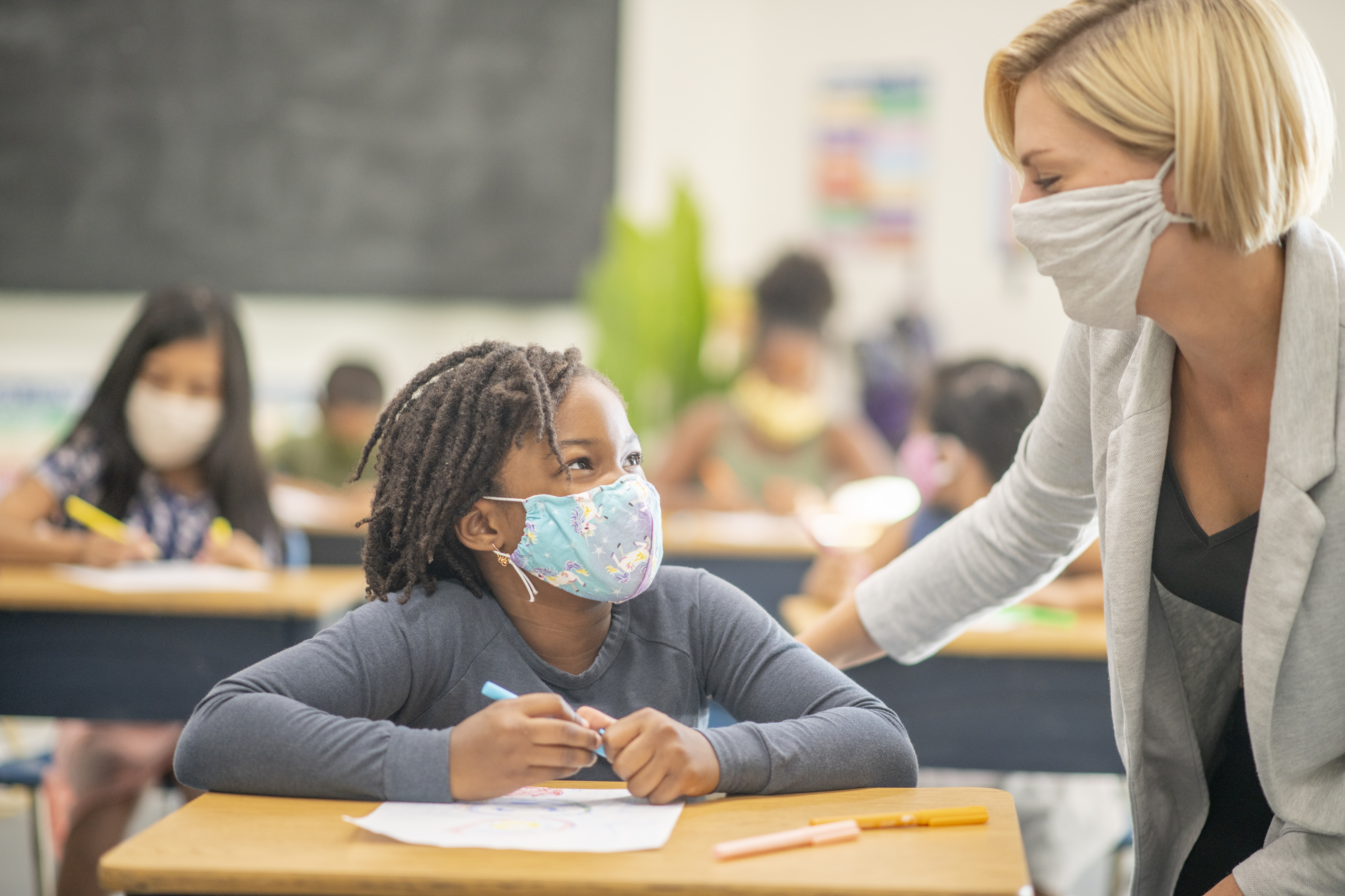 Female student wearing a reusable face mask while sitting at her desk in class.